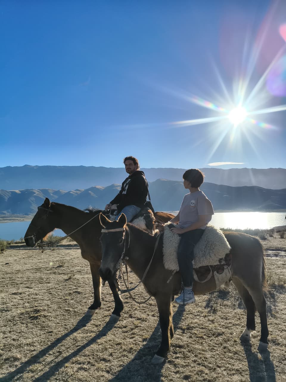 Cabalgata al atardecer con el sol sobre las montañas y el Dique La Angostura, El Mollar, Tafí del Valle