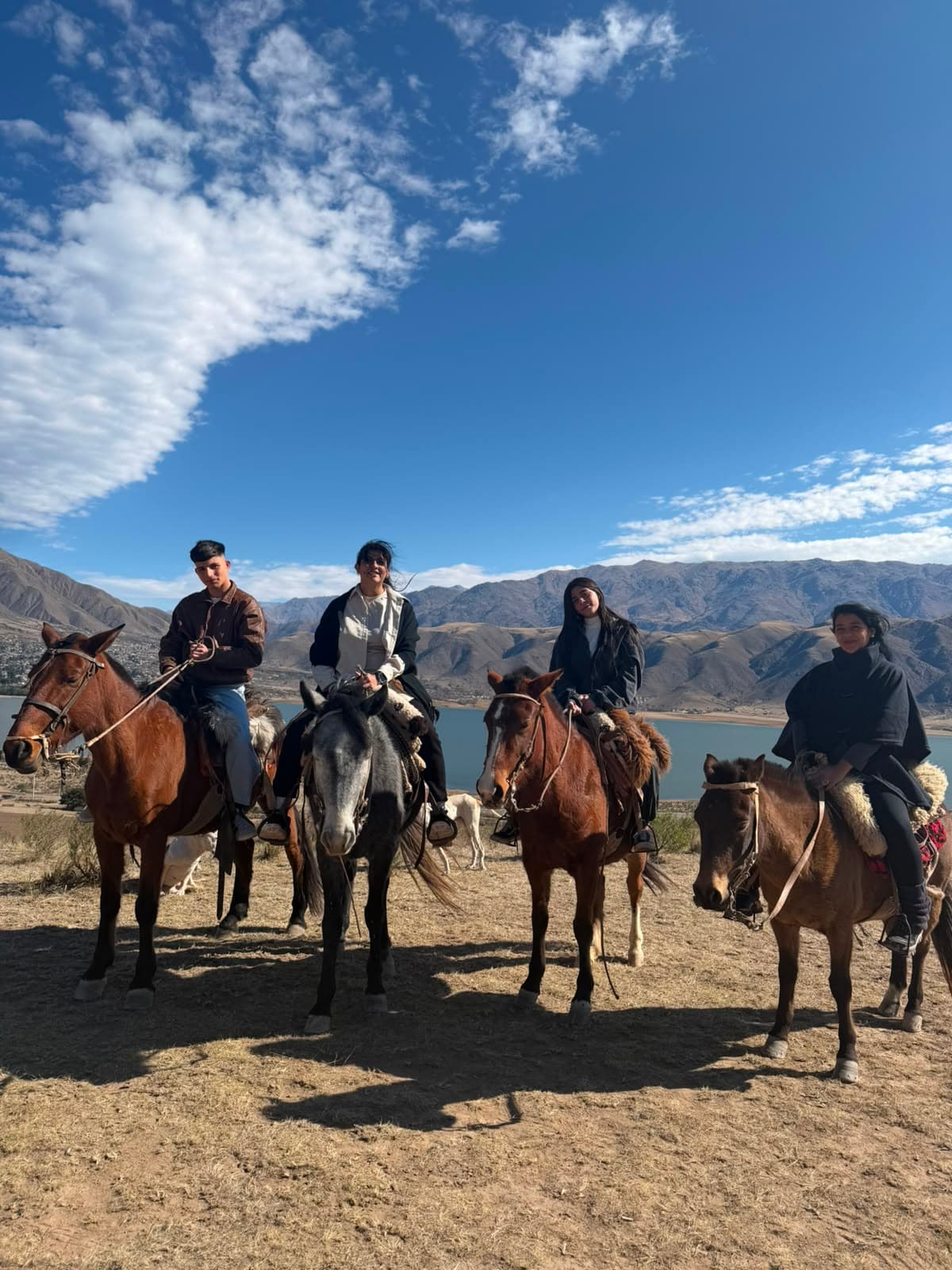 Grupo de amigos a caballo posando frente al Dique La Angostura en El Mollar